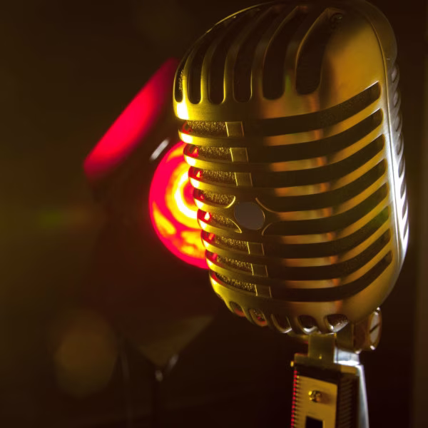 Vintage golden microphone against a dark background with red light.