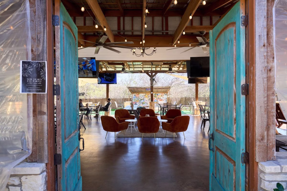 Open turquoise doors frame a covered patio with chairs.