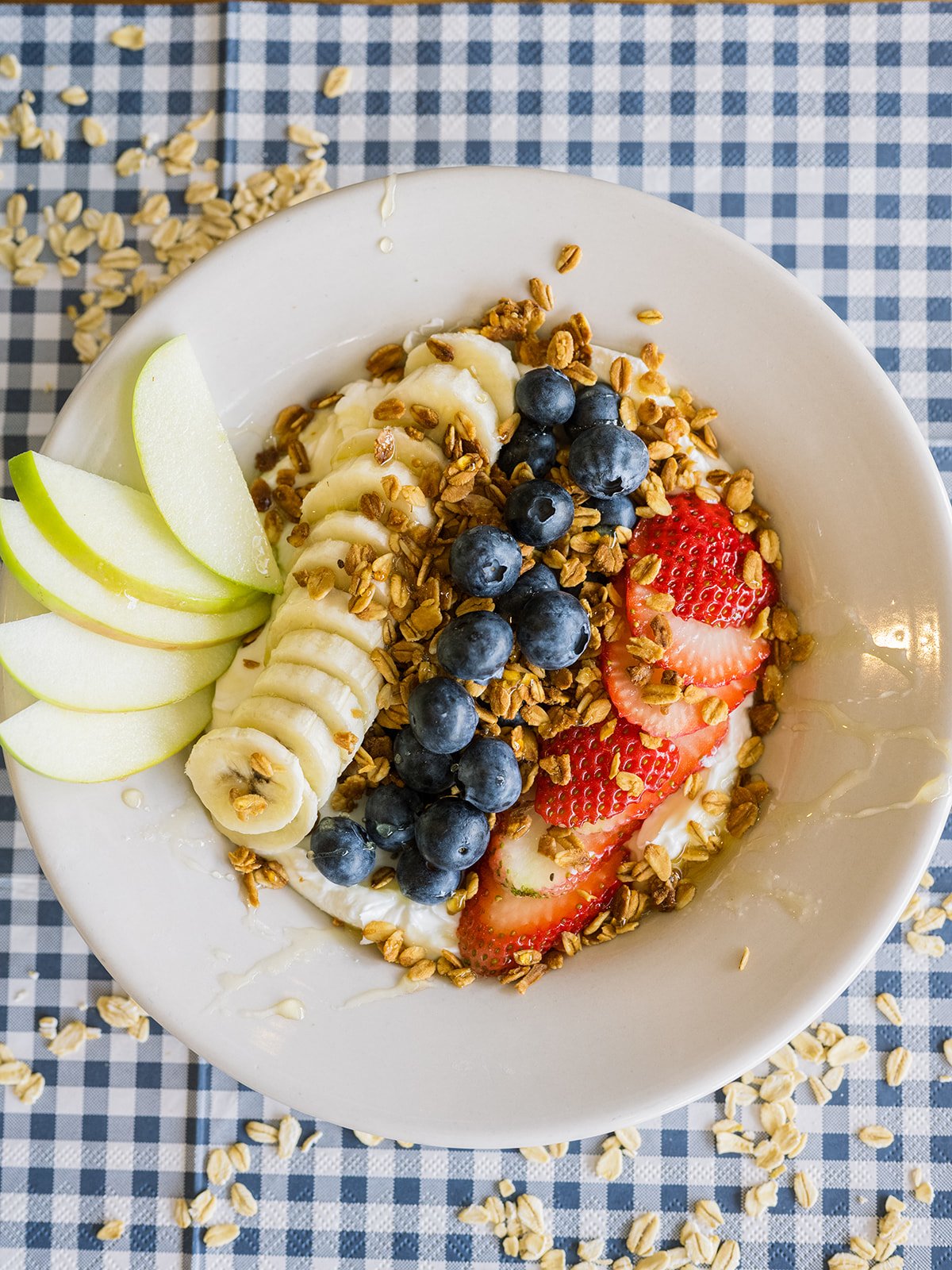 Yogurt bowl with mixed fruit, granola, and apple slices.