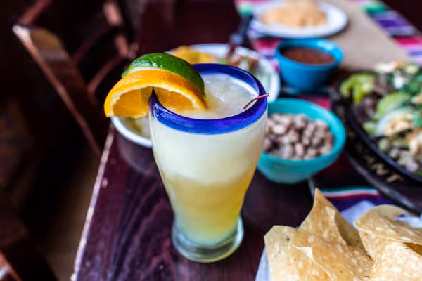 Frozen drink with orange and lime in a blue-rimmed glass.