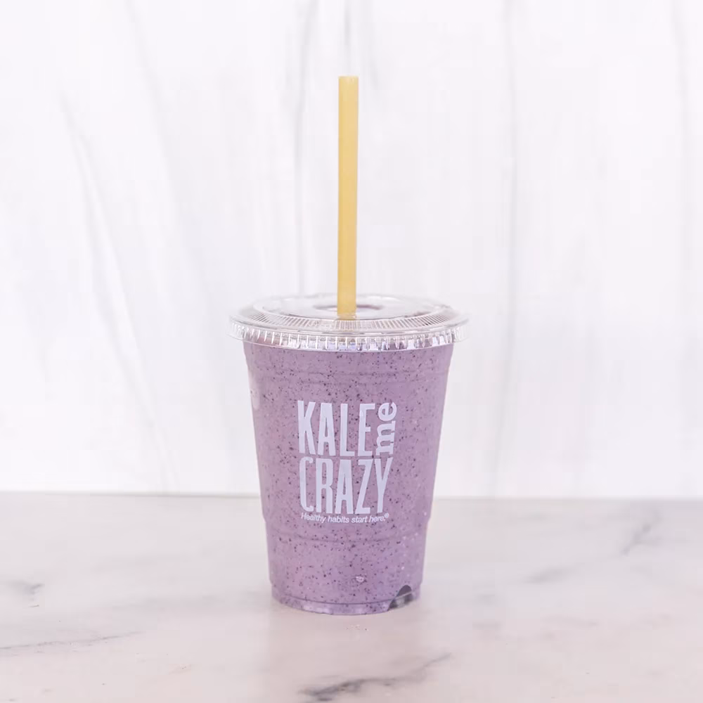 Purple smoothie in a plastic cup with straw and KALE & ME CRAZY logo.