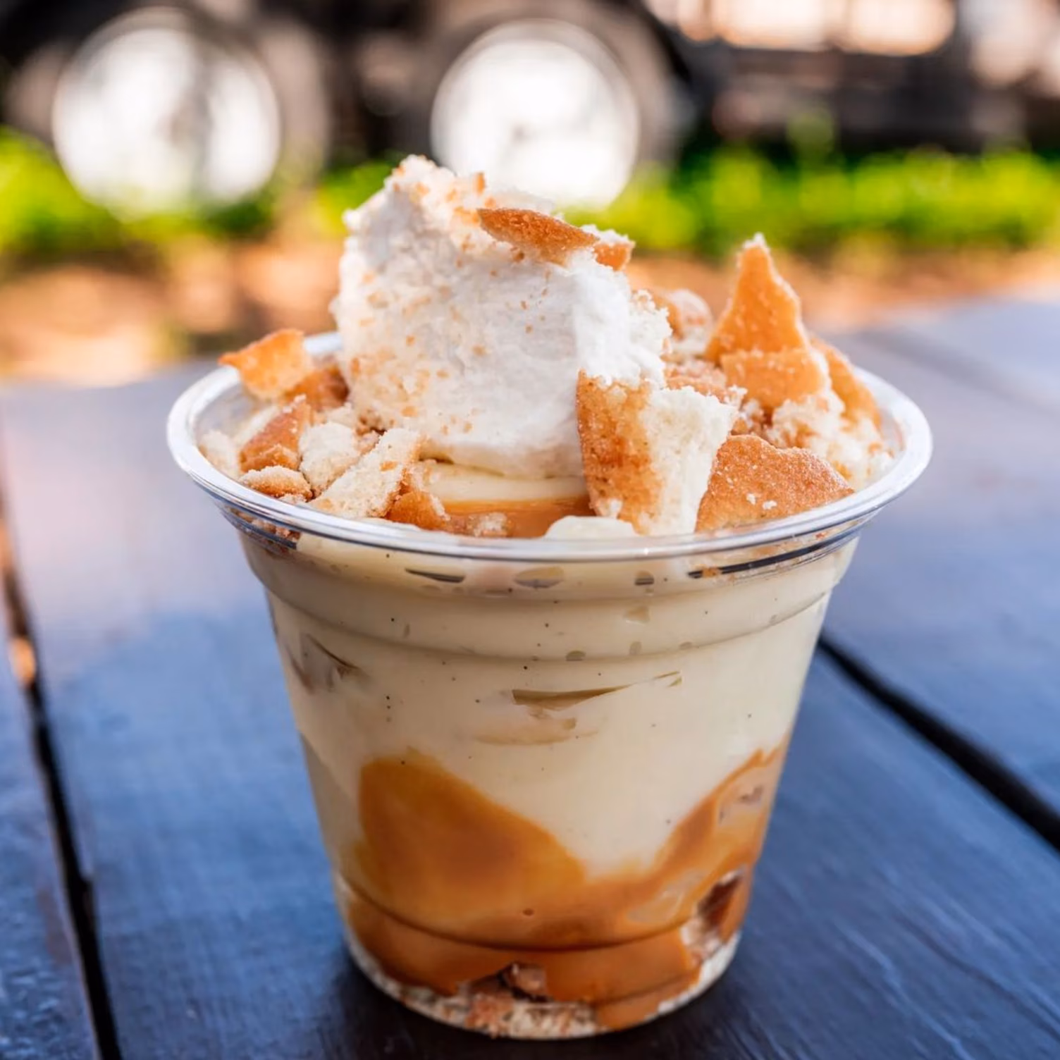 Layered creamy dessert cup with caramel, cookie crumbs, whipped topping.