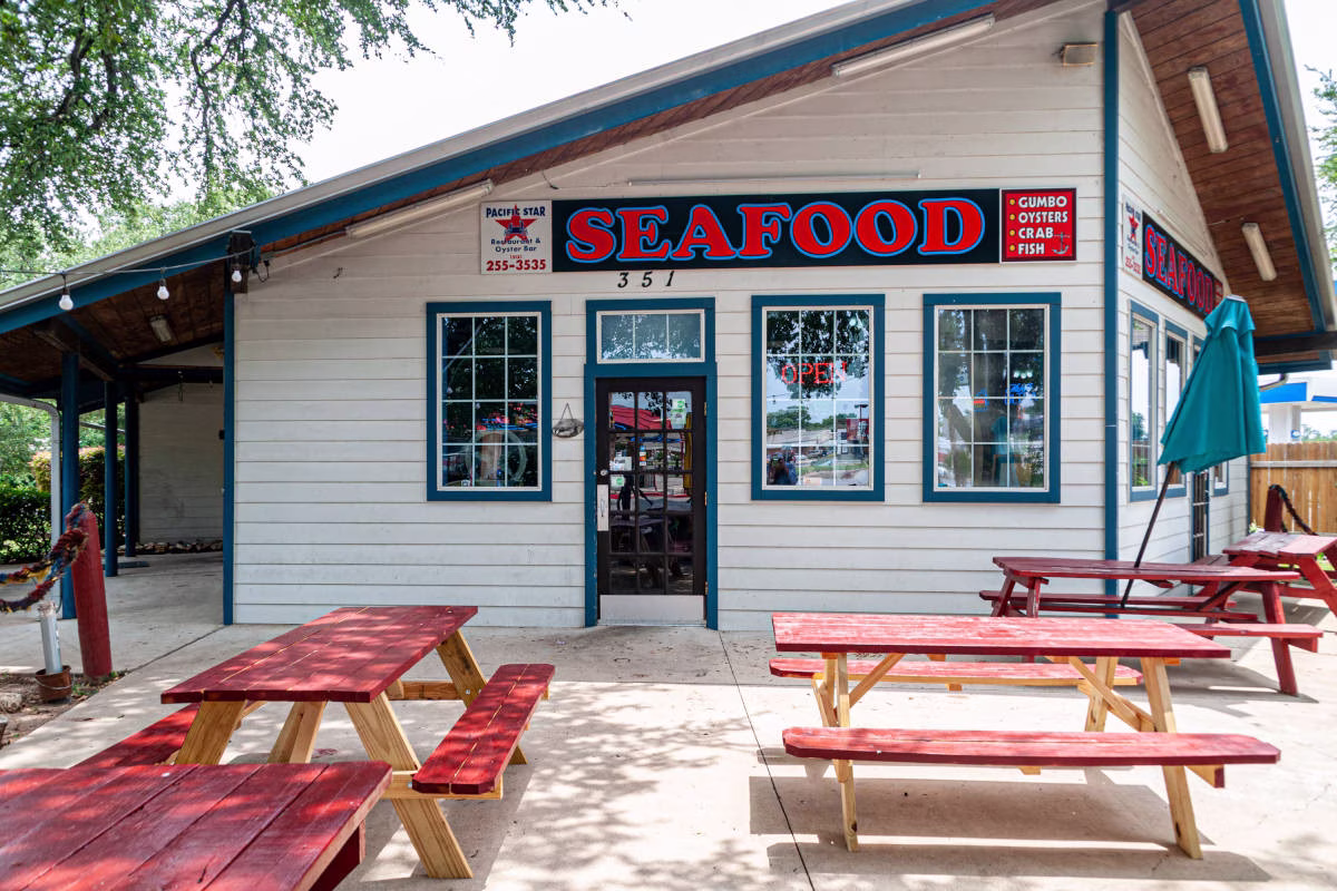 Seafood restaurant building with outdoor red picnic tables.