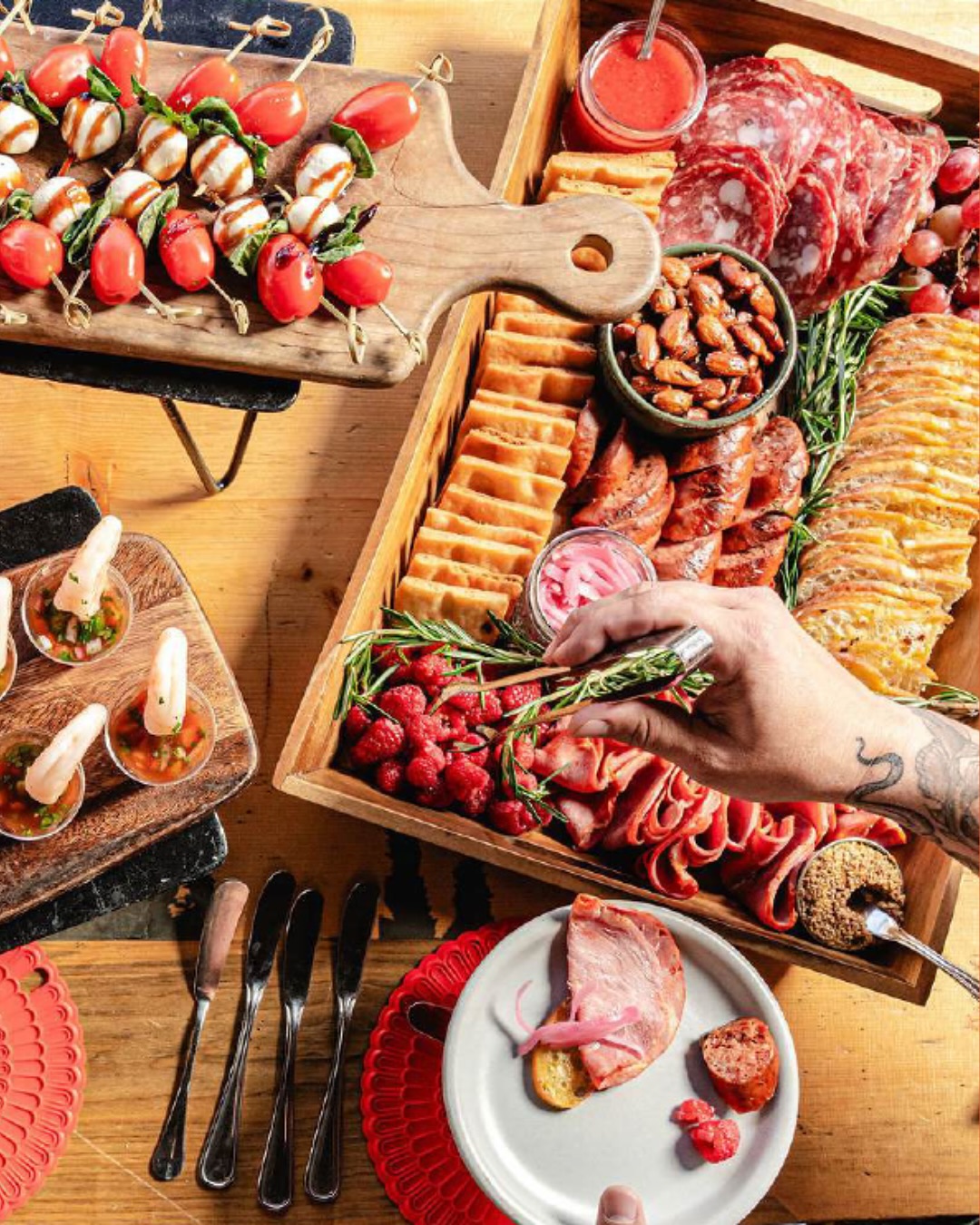 Large charcuterie board, caprese skewers, shrimp cocktails on wooden table.