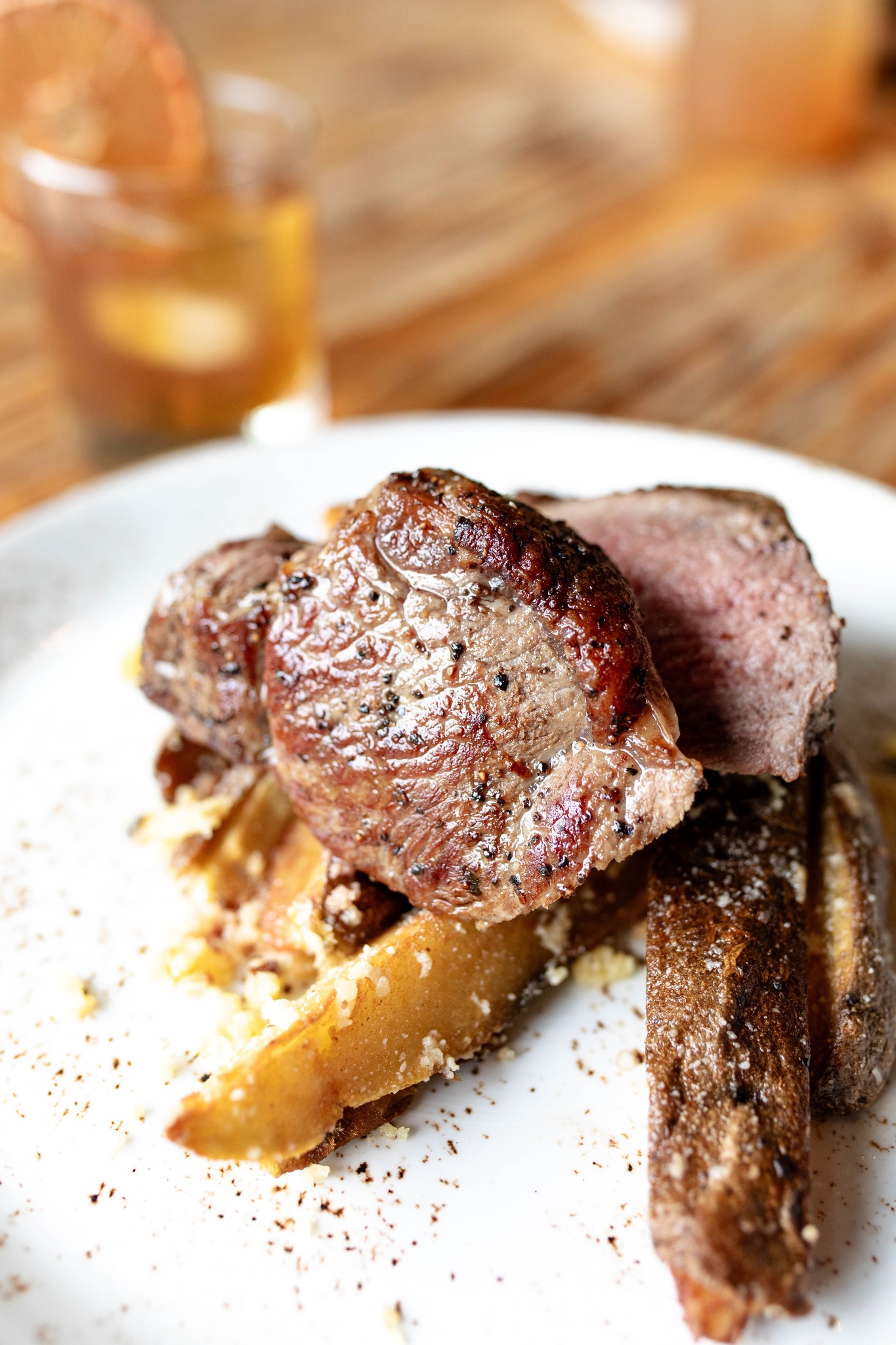 Seared meat cuts with pepper, served on potato wedges.