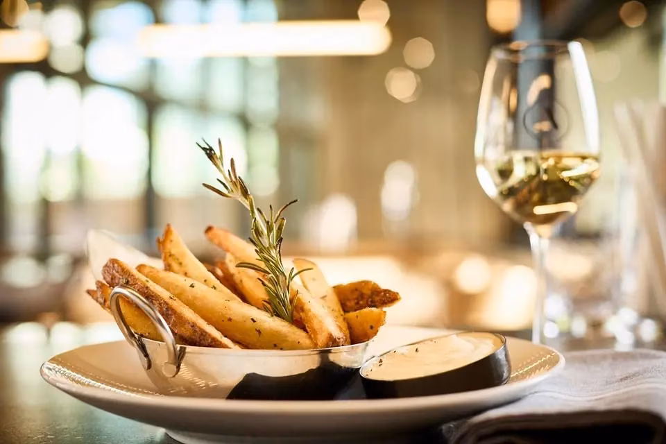 Potato wedges with rosemary, dipping sauce, and white wine at a restaurant.