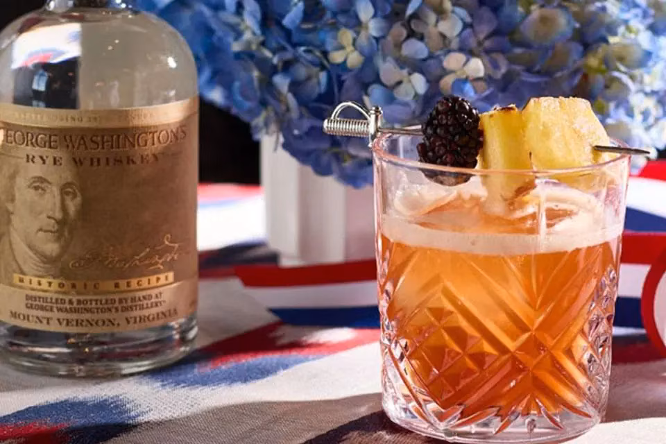 George Washington's Rye Whiskey bottle and cocktail with blackberry, pineapple garnish.
