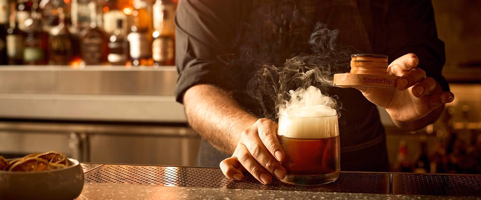 Bartender smoking a cocktail using a 'SmokeTop' device.