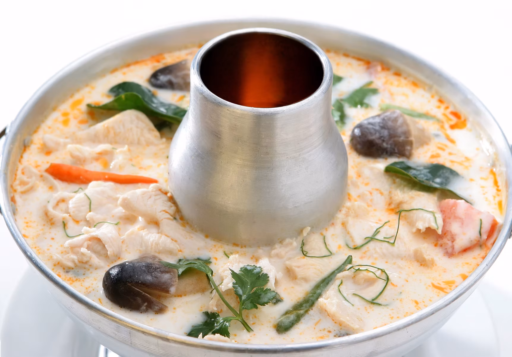 Creamy chicken soup with mushrooms and herbs in a hot pot.
