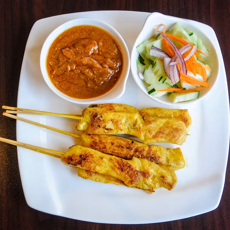 Chicken satay skewers with peanut sauce and pickled cucumber salad.