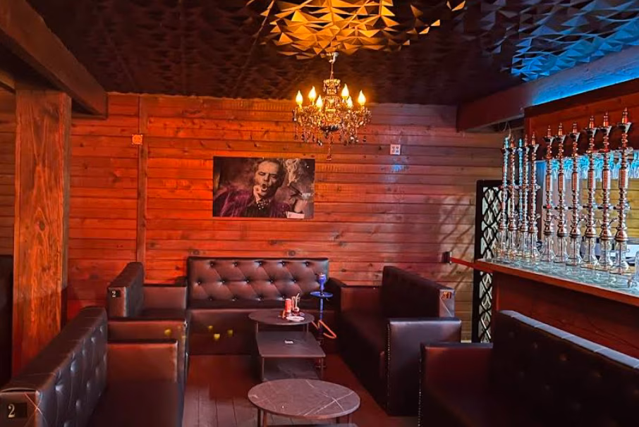 Moodily lit hookah lounge with wooden walls and leather seating.