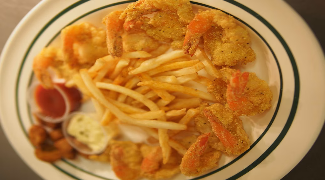 Fried shrimp and french fries on a plate with two dipping sauces.