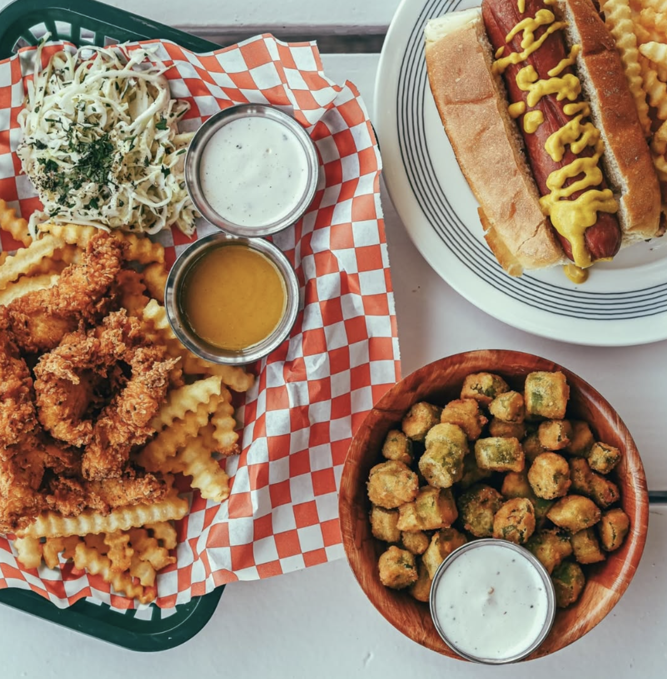 Fried chicken, hot dog, fries, coleslaw, and fried okra with sauces.