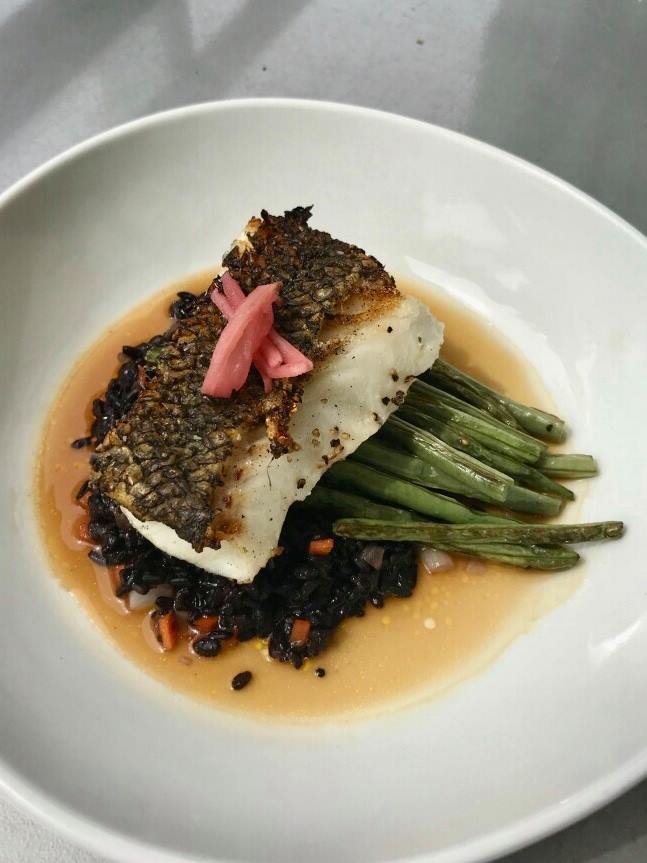 Pan-seared fish with black rice, green beans, pickled ginger, and sauce.