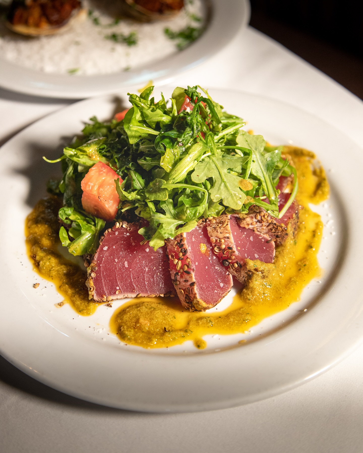 Seared tuna with arugula salad and yellow sauce.