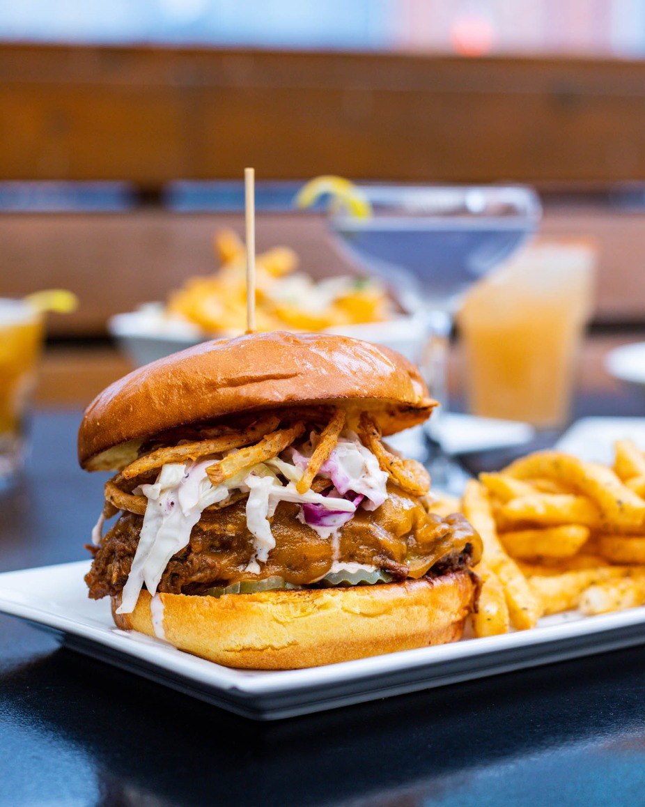 Pulled pork sandwich with coleslaw, fried onions, and french fries.