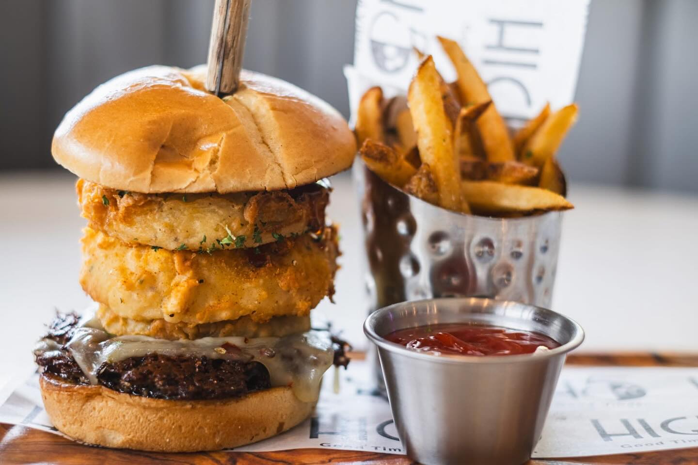 Cheeseburger with fried rings, a cup of fries, and ketchup.