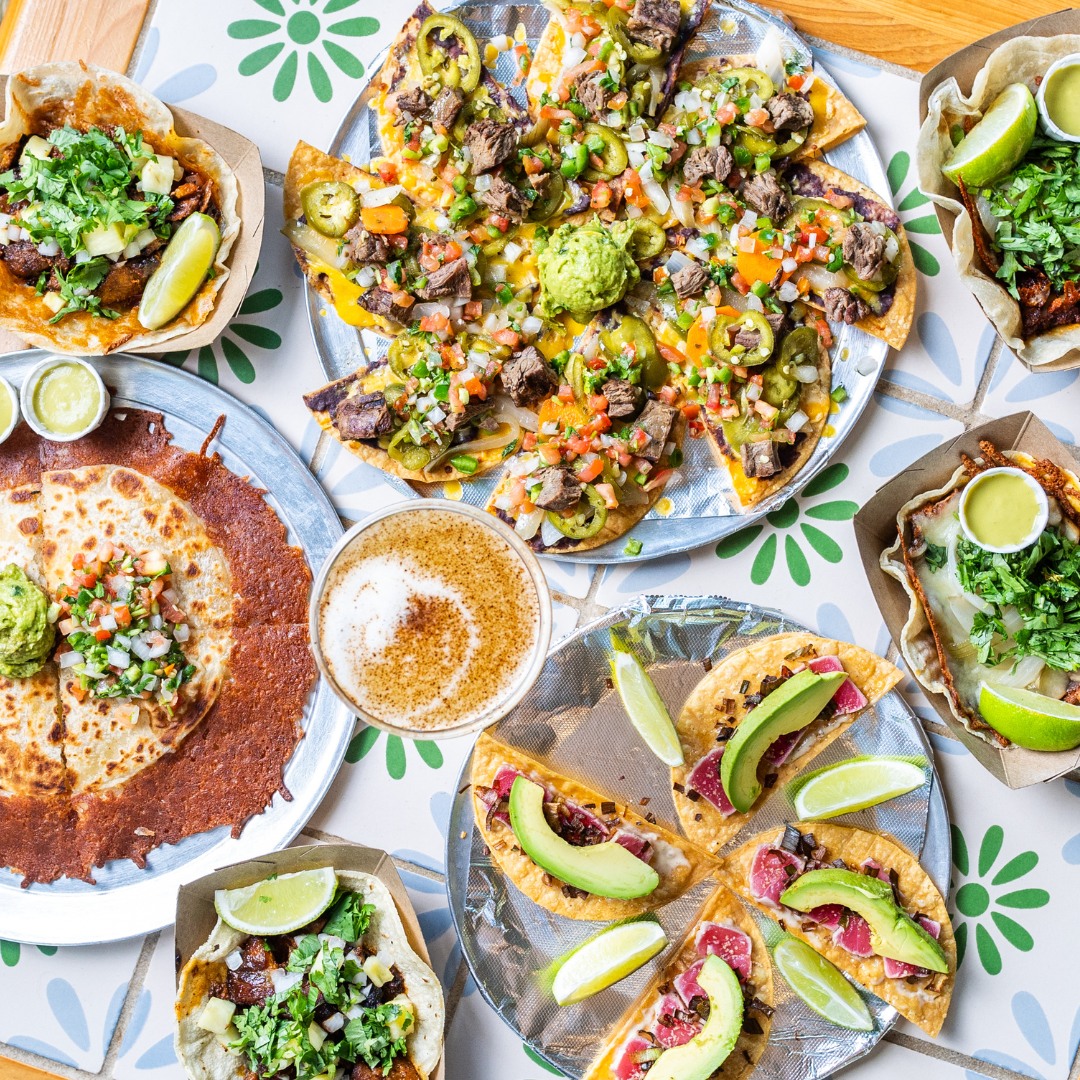 Overhead view of various Mexican dishes: nachos, tacos, quesadillas, and coffee.