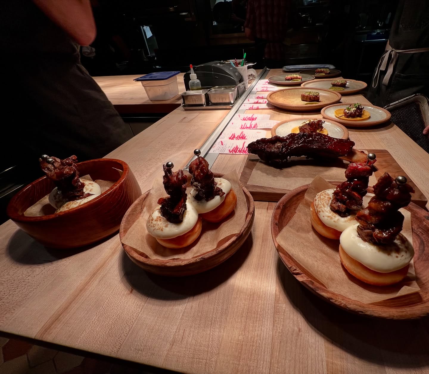 Meat skewers on dough, large rib, and dishes on a counter.