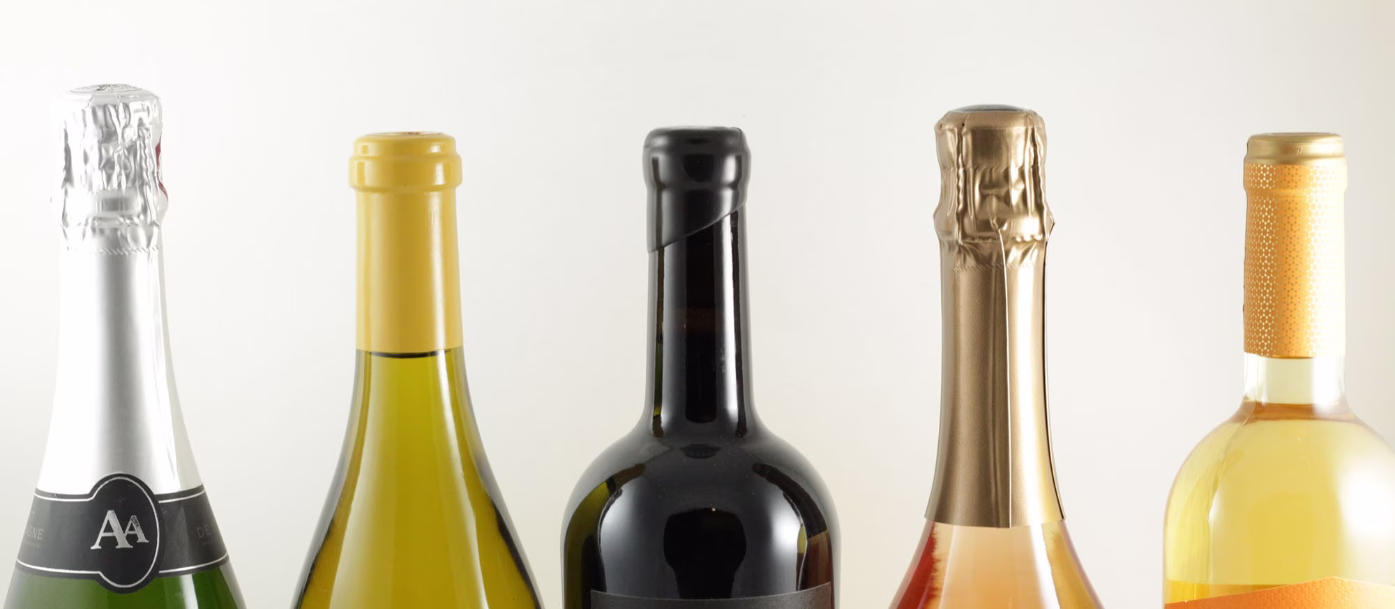 Five different wine bottles with varying colors and closures.