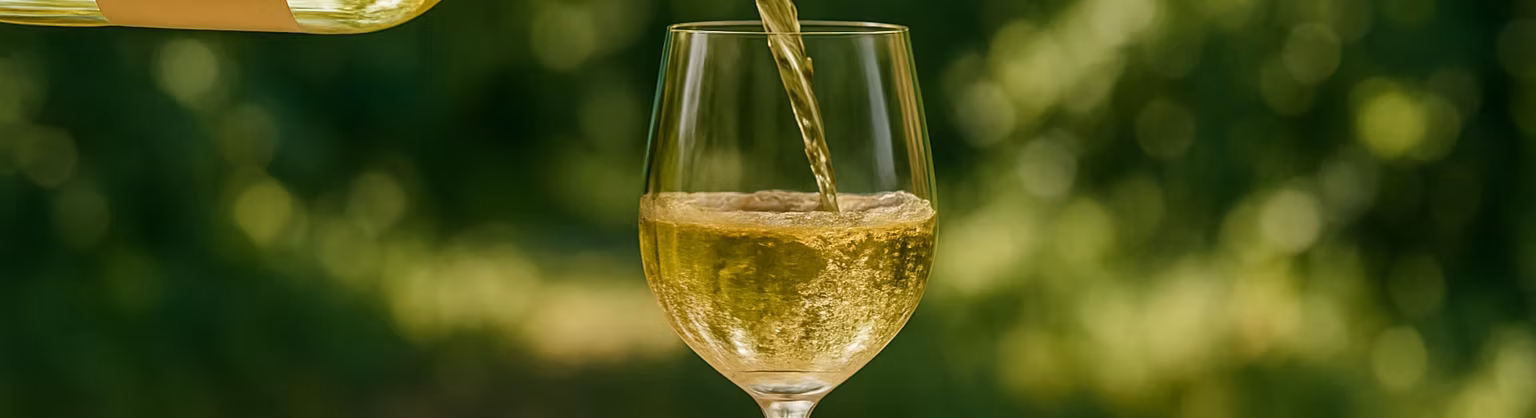 White wine being poured into a glass with a green background.