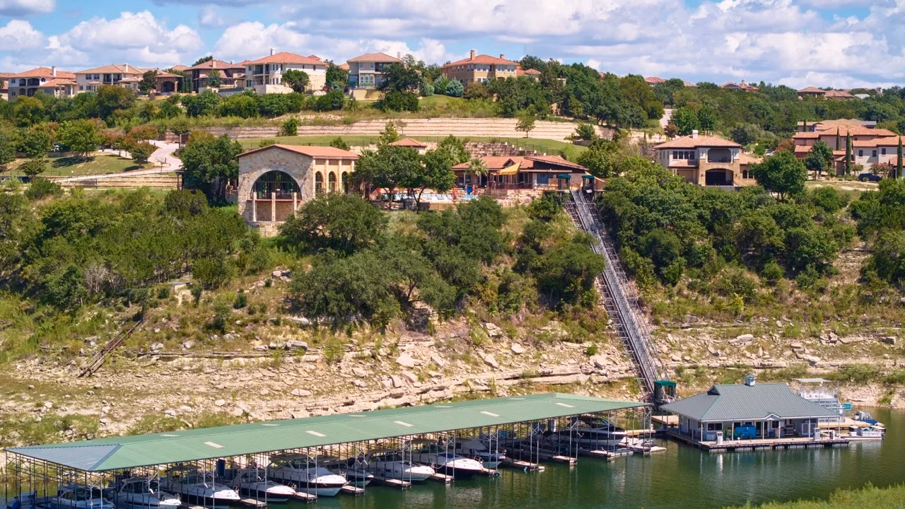 Hillside homes, boat marina, and incline elevator by low lake water.