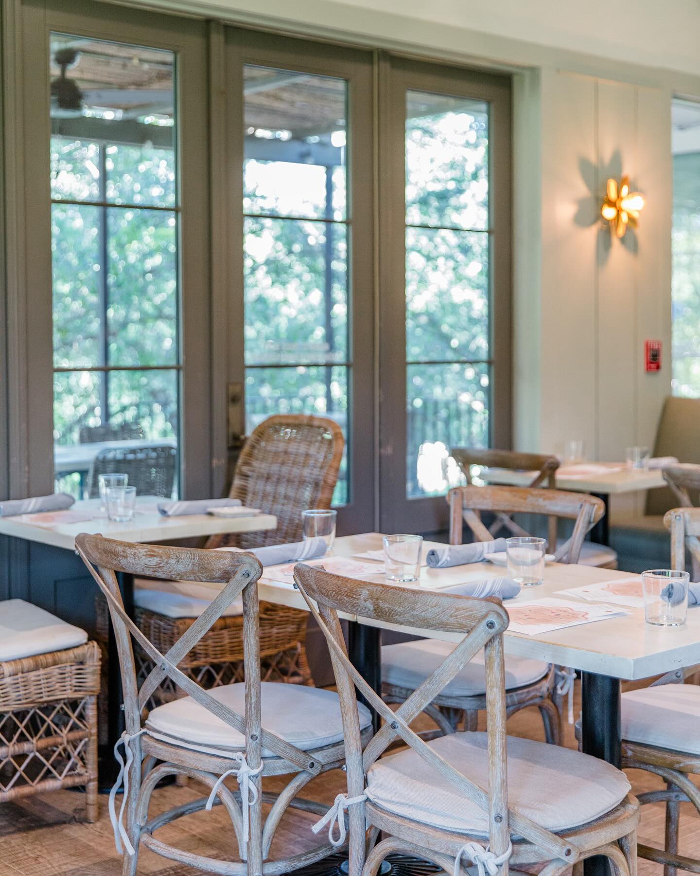 Dining room with wooden chairs, set tables, and large windows.