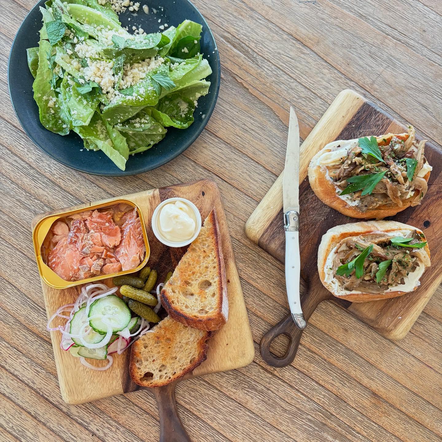 Overhead shot of a meal with salad, tinned fish, and mushroom toasts.