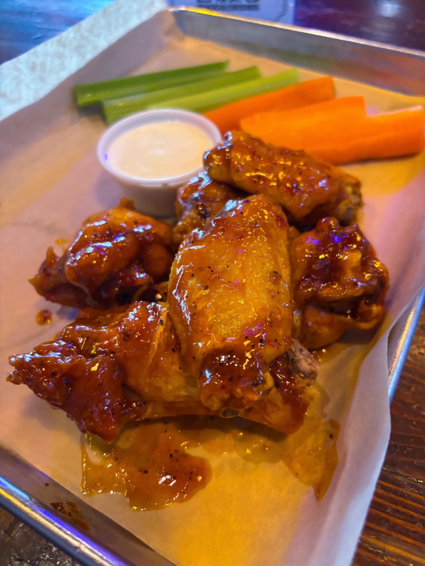 Saucy chicken wings, white dip, celery, and carrot sticks.