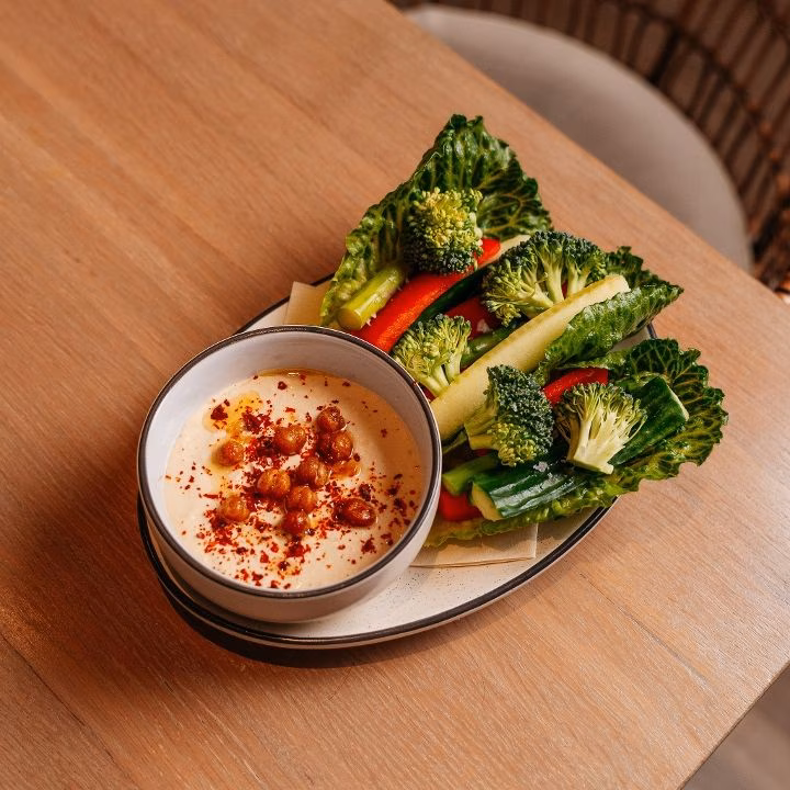 Bowl of hummus with spiced chickpeas and various raw vegetables.
