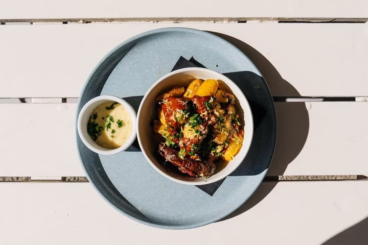 Overhead view of potato dish with sauce and dip on a tray.