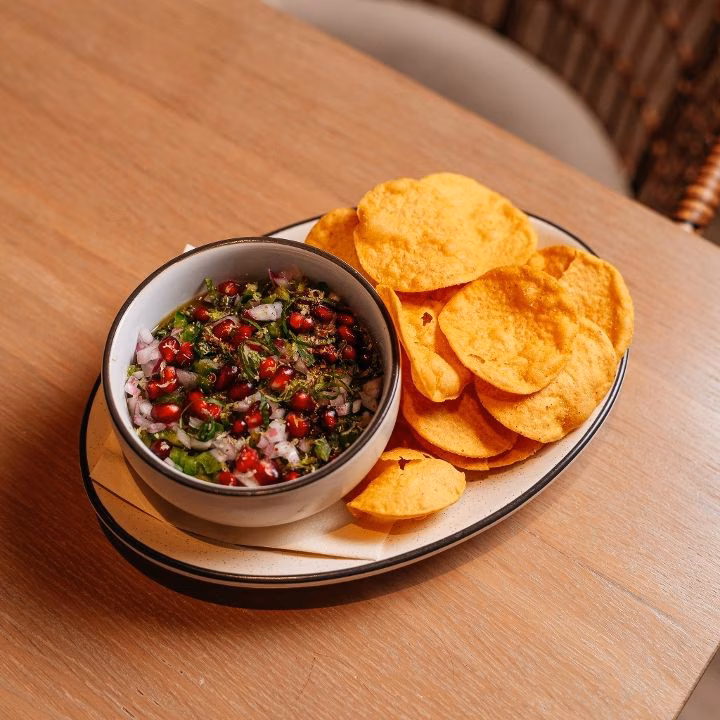 Pomegranate and onion dip served next to crispy round chips.