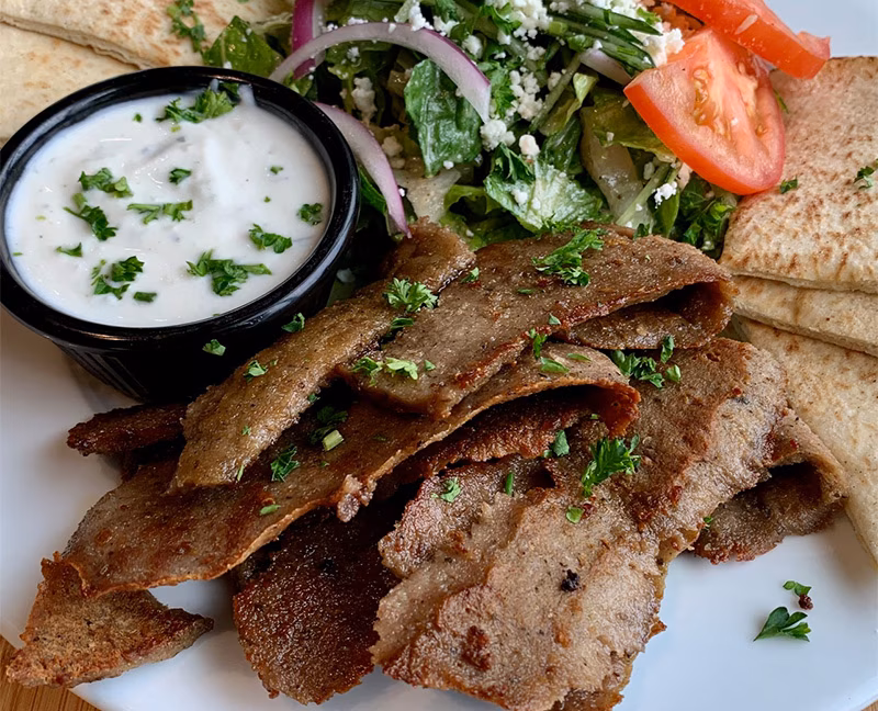 Plate of gyro meat, tzatziki, Greek salad, and pita bread.