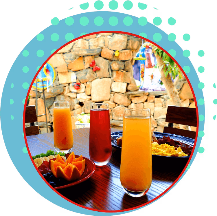 Table with three juices, fruit, and breakfast items outdoors.
