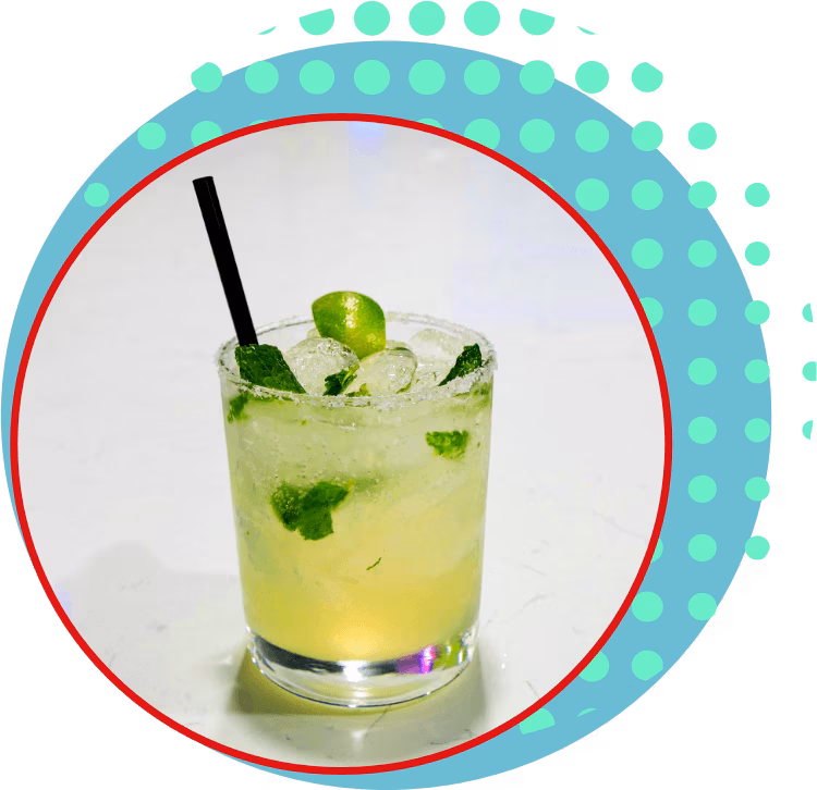 Light green drink in a glass with ice, mint, lime, and straw.