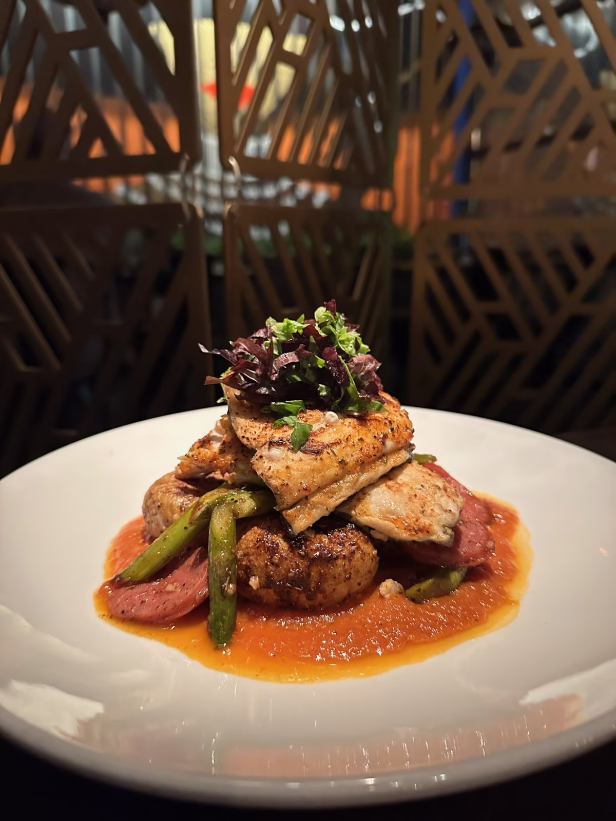 Grilled fish, roasted potatoes, asparagus, and greens with red sauce.