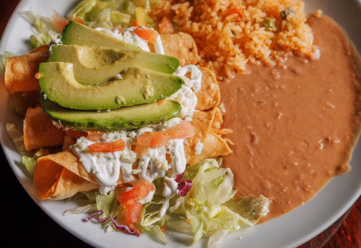 Taquitos with avocado, sour cream, lettuce, rice, and refried beans.