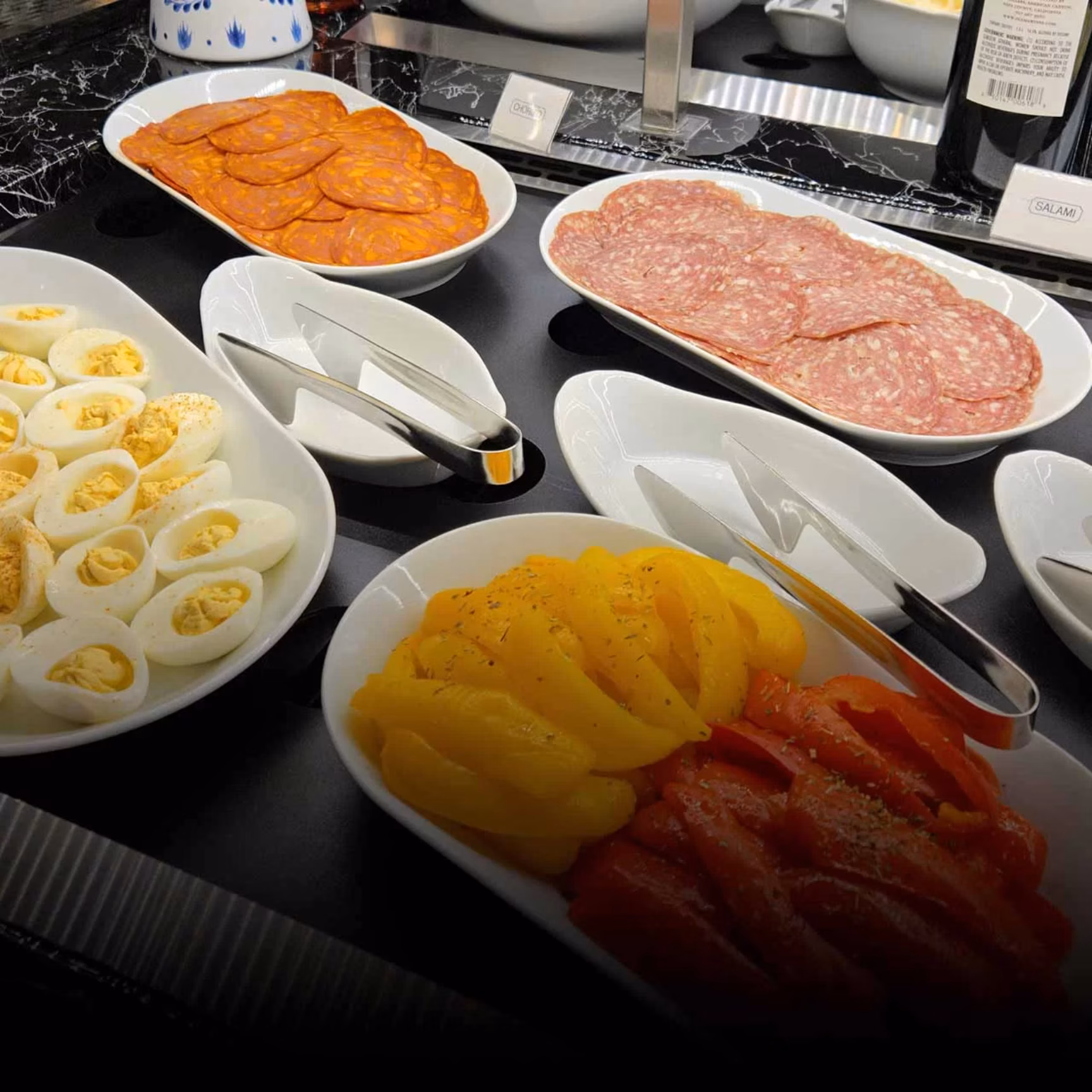 Plates of hard-boiled eggs, chorizo, salami, and bell peppers.
