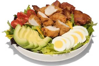 Salad with fried chicken, avocado, sliced eggs, and tomatoes.