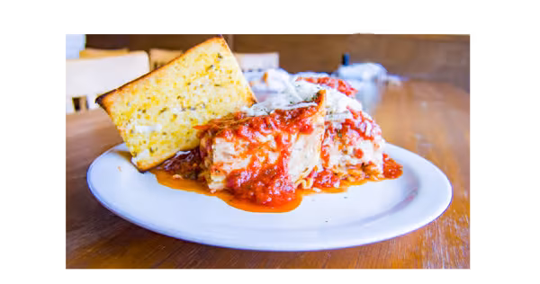 Lasagna with red sauce, cheese, and a slice of garlic bread.