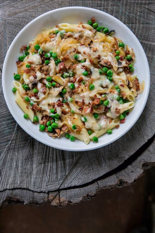 Penne pasta with peas, bacon, melted cheese, and caramelized onions.