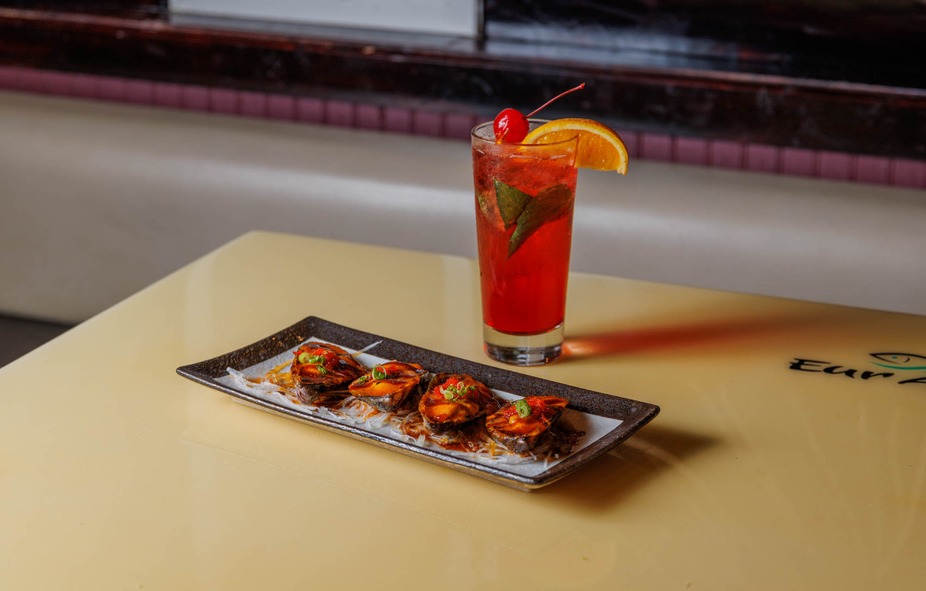 Plate of four food items and a red drink with orange and cherry.