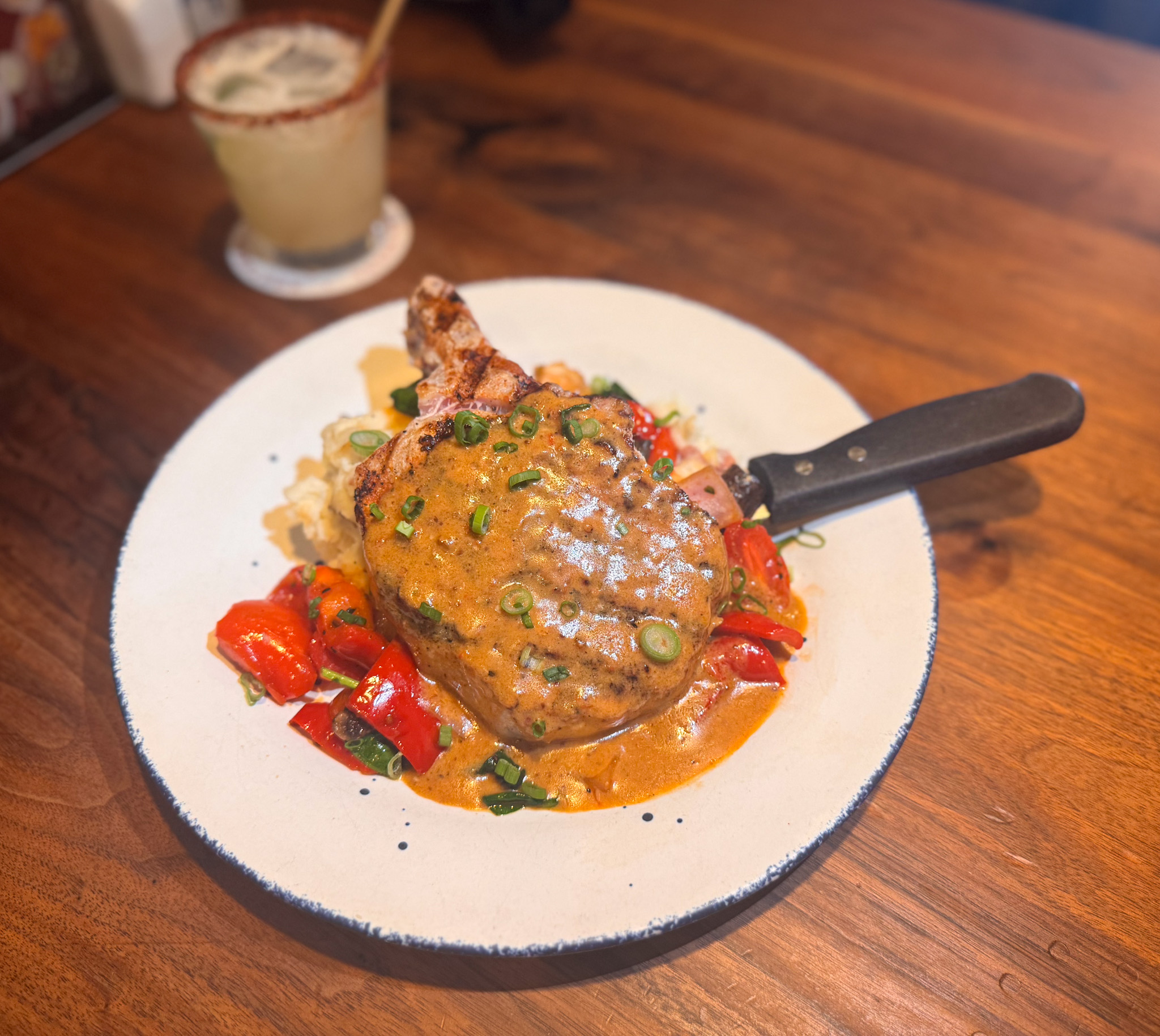 Pork chop with creamy sauce, roasted red peppers, mashed potatoes.