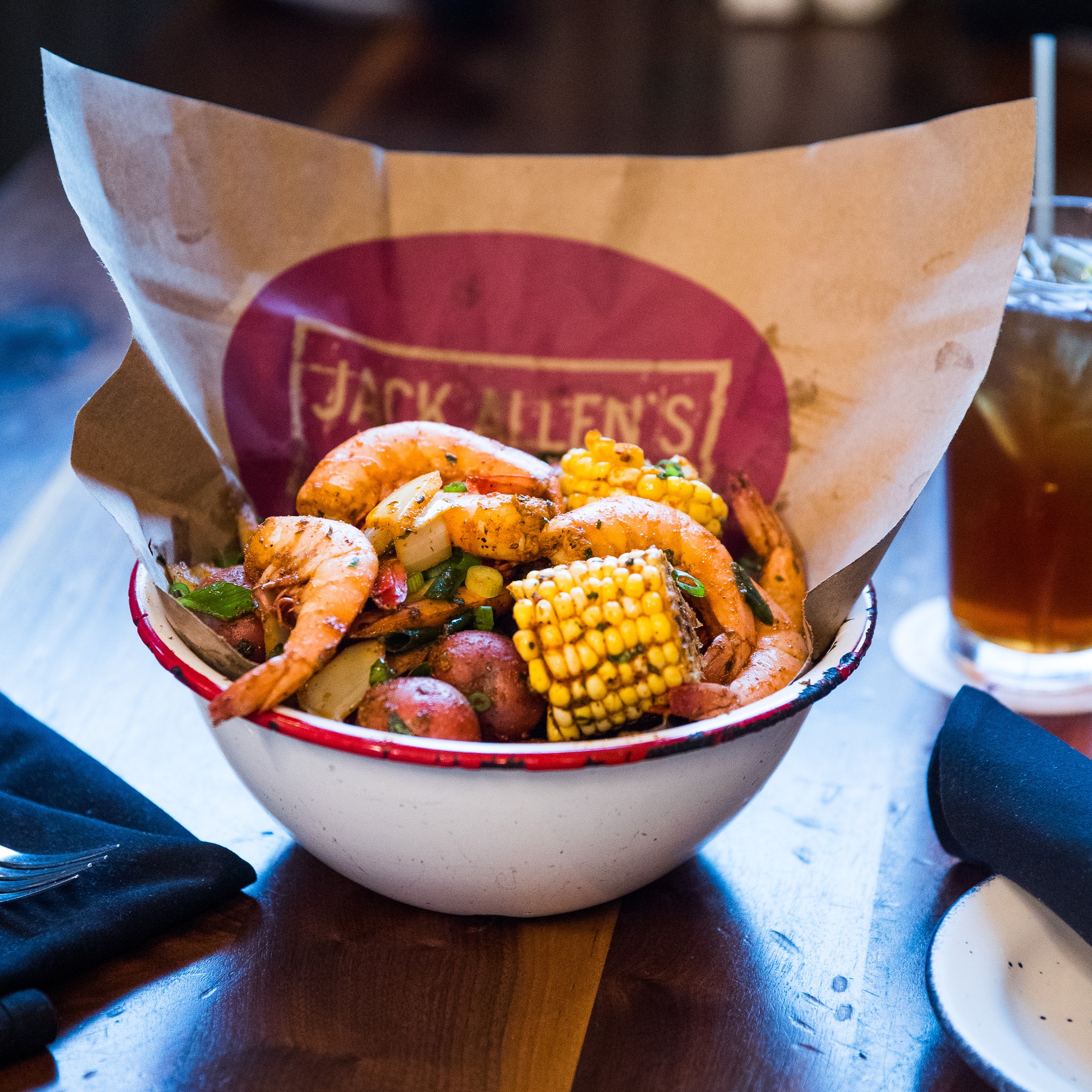 Shrimp, corn, and potatoes in a bowl lined with Jack Allen's paper.