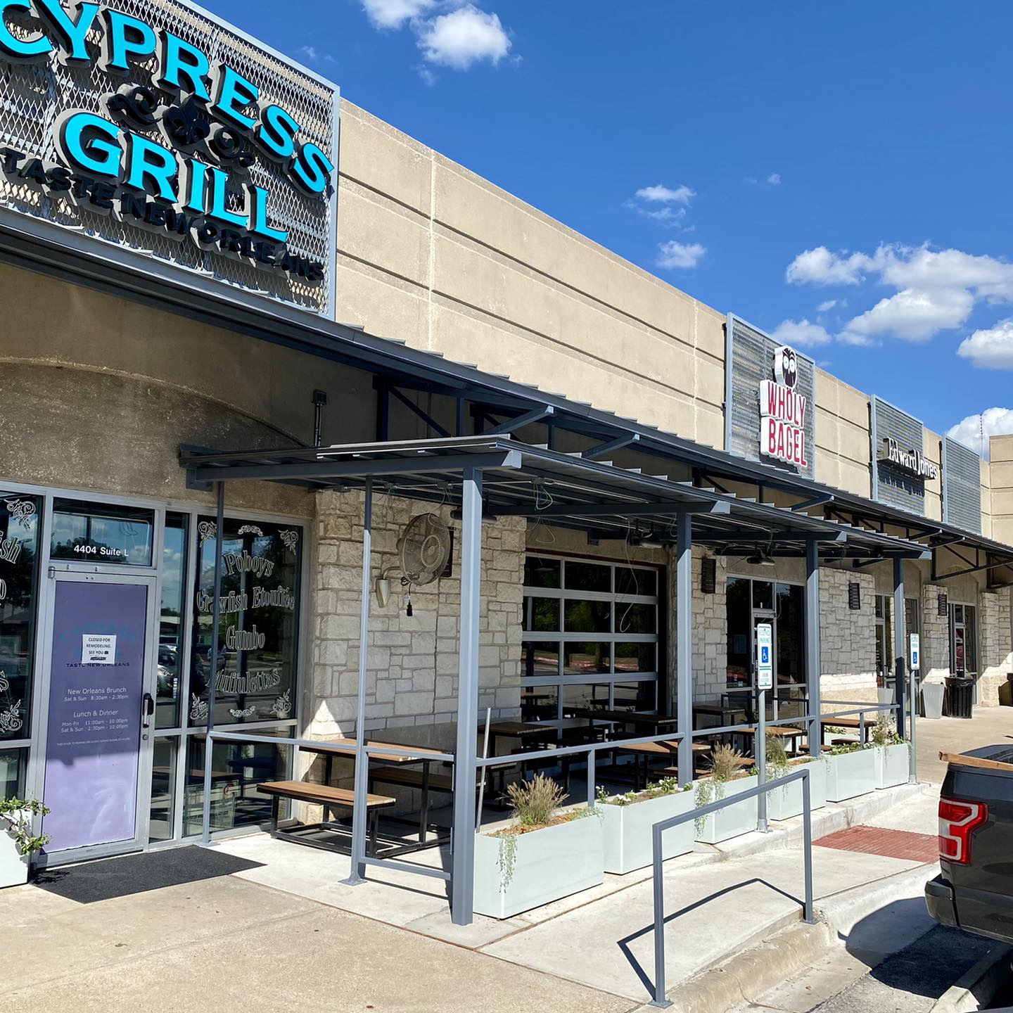 Exterior of Cypress & Grill and Wholy Bagel with outdoor seating.
