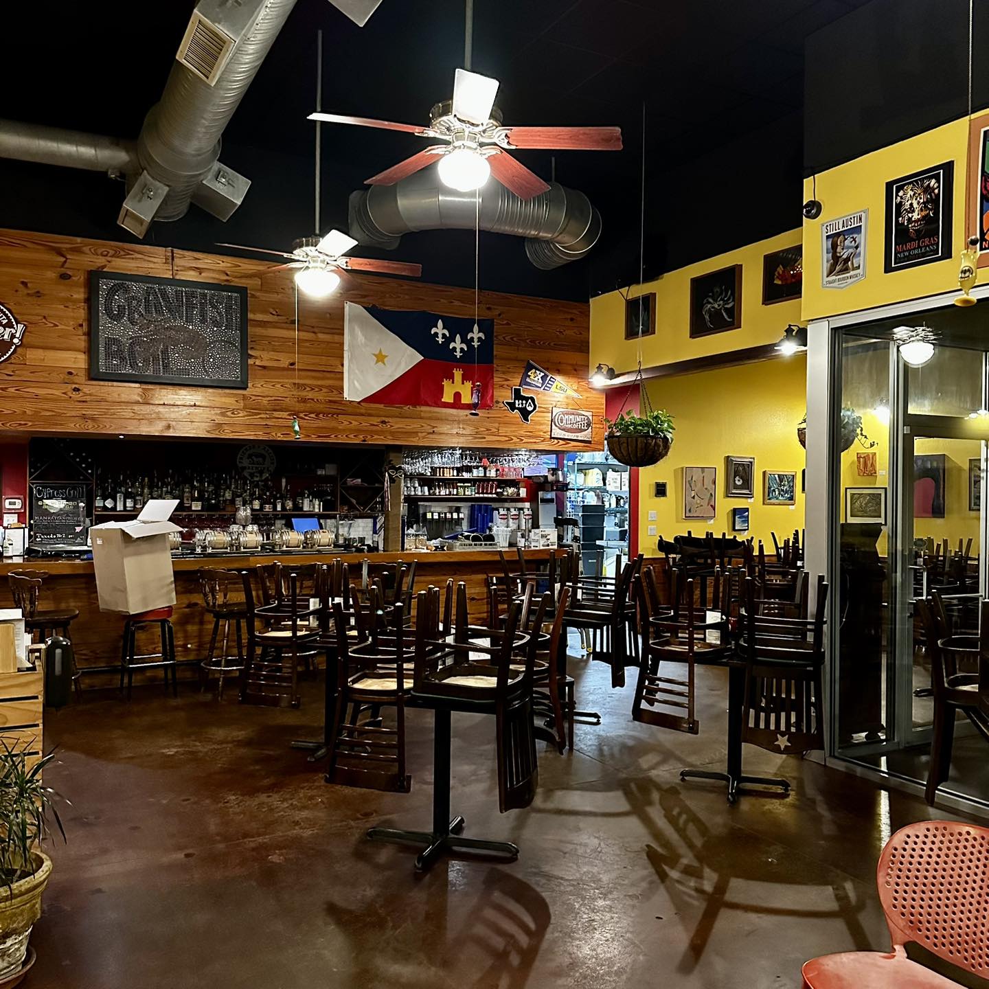 Restaurant bar interior with stacked chairs, wooden walls, and a flag.