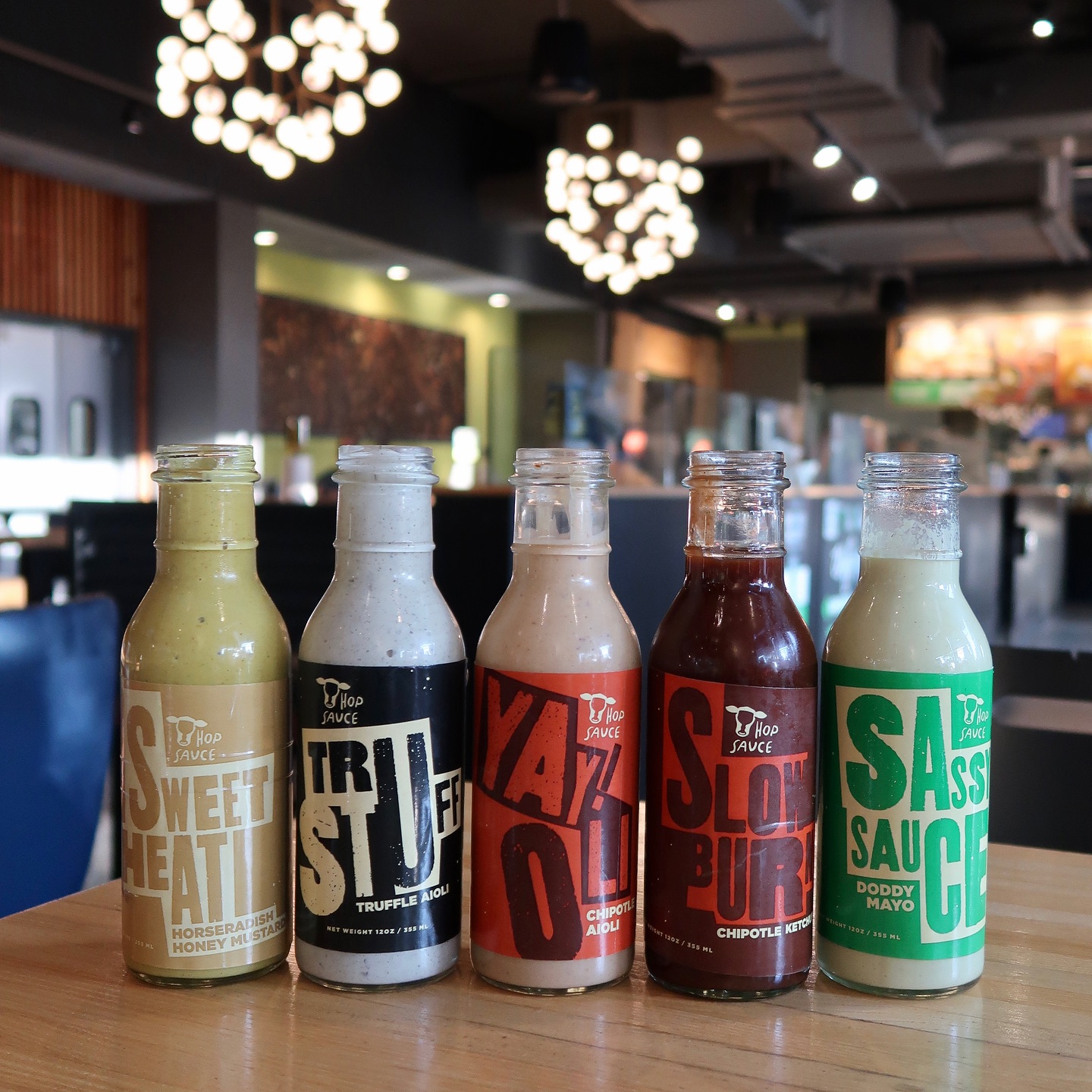 Five bottles of Hop Sauce on a table in a restaurant.