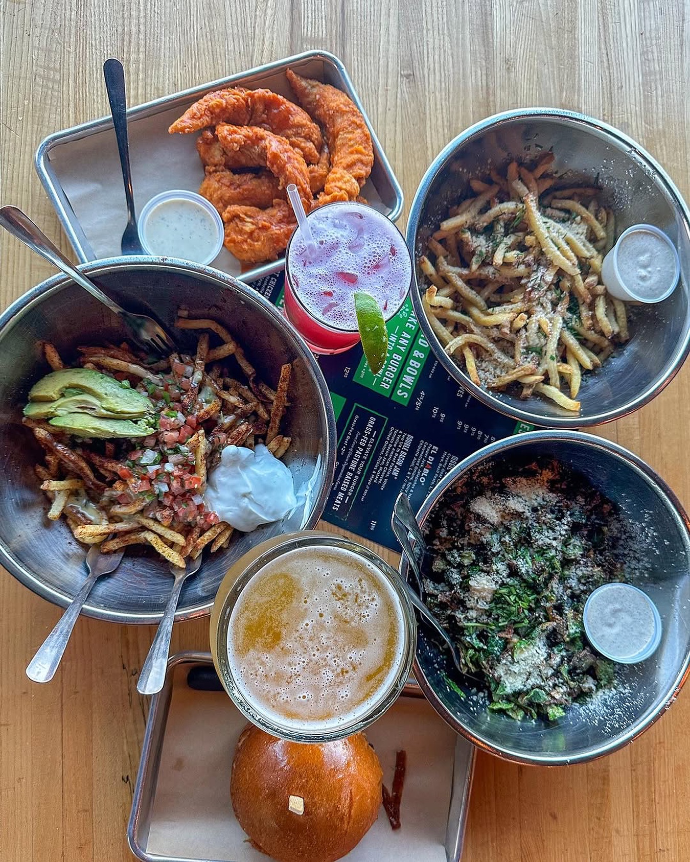 Overhead view of chicken tenders, fries, salad, beer, and a cocktail.