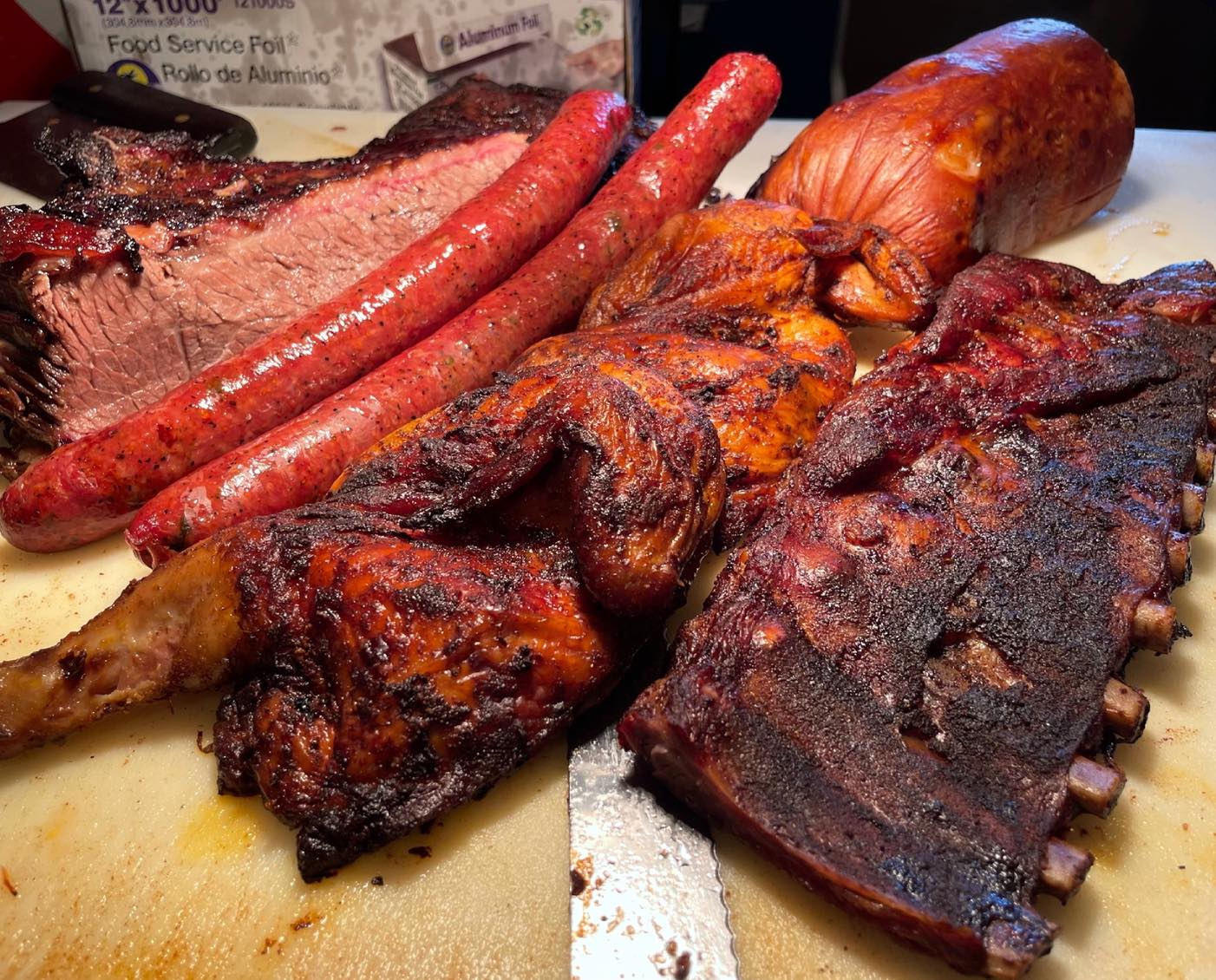 A large platter of various smoked meats, including ribs, brisket, and sausage.