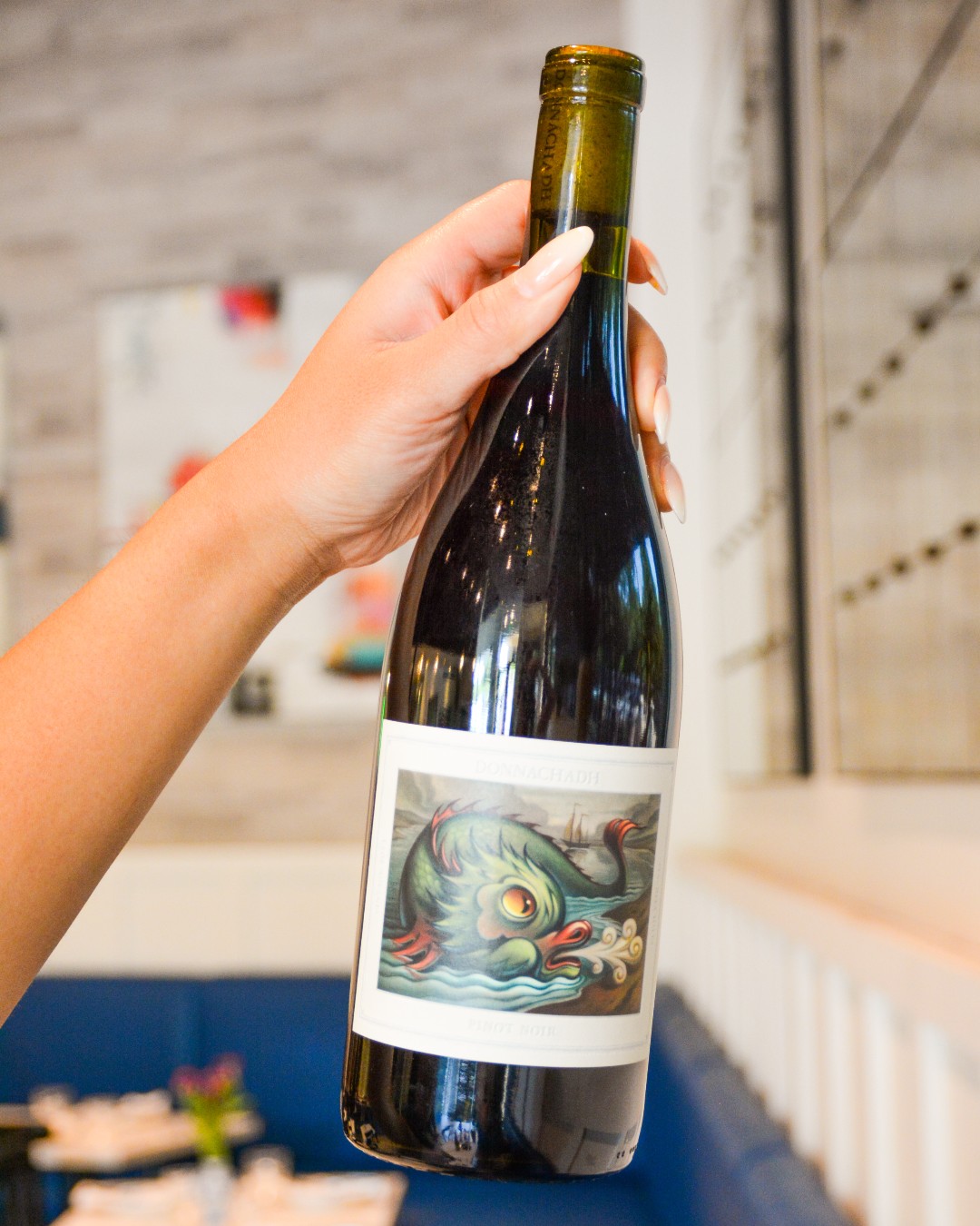 Hand holds a bottle of Donnachadha Pinot Noir with sea creature label.